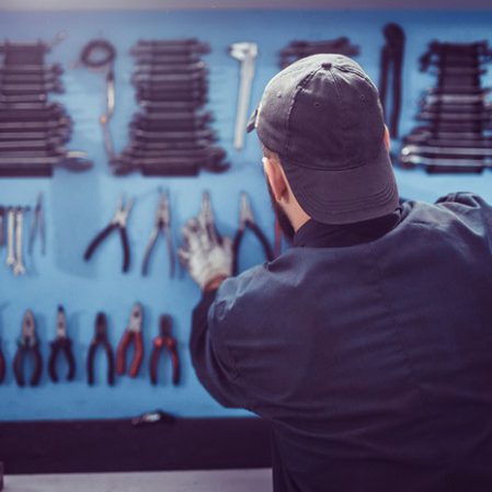 Handwerker hängt Werkzeug an der Wand auf