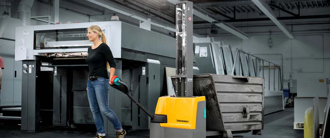 Frau zieht einen beladenen Monomast-Elektro-Hochhubwagen